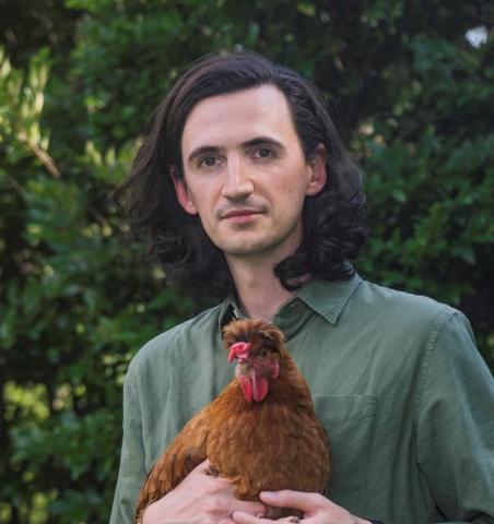 A photograph of Piers Gelly holding a chicken.